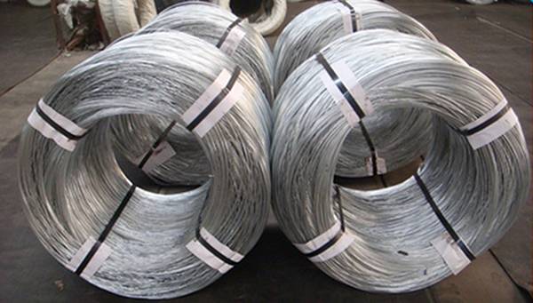 Three coils of galvanized oval wires on the ground.